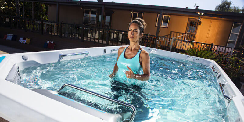 Lady considering buying and exercising in and comparing swim spas